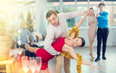 Happy group of people having fun celebrating Christmas and dancing waltz or tango