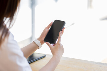Mockup woman hand holding using smart phone with white blank screen at coffee shop, mobile app design and advertising,SME entrepreneur online marketing