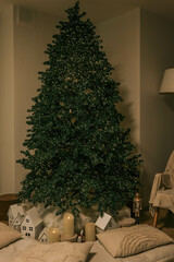 Minimalistic Christmas interior with a lit Christmas tree, soft pillows, glowing candles, and small decorative houses, creating a cozy and festive atmosphere