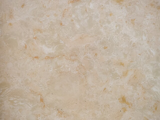 A close-up of a natural stone with a beige background and intricate patterns of white and orange veins