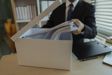 An office worker is putting important documents in boxes to prevent loss. A businessman is putting...