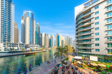 A wooden Dhow boat cruises along the Dubai Marina surrounded by modern skyscrapers as visitors...