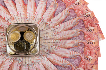 Coins of 100 and 200 Kazakhstan tenge in a glass jar and banknotes of 5000 tenge