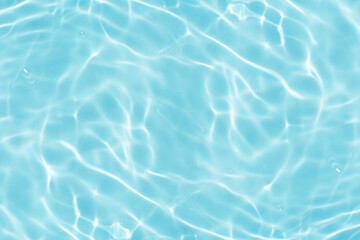 Blue water with ripples on the surface. Defocus blurred transparent blue colored clear calm water surface texture with splashes and bubbles. Water waves with shining pattern texture background.