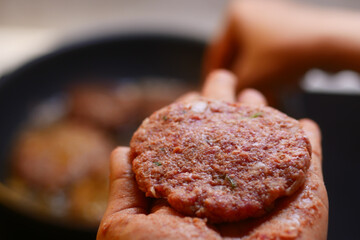 Freshly prepared, cooked burger patty held in hand, ready to enjoy