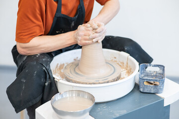 Close-up of a potter's hands working on a pottery wheel. 