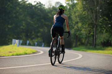 Naklejka premium Woman cyclist riding bike in summer park