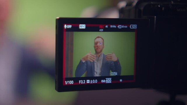 Male youtuber influencer recording a video for social media in green screen studio talking into the camera