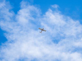 Small ultralight airplane with overhead wing and single propeller flying in sunset sky.
