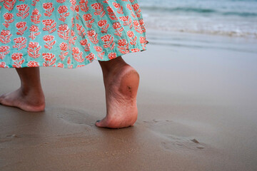 Closeup of a female's bare feet walking at a beach at the morning. Concept of the travel, vacation.