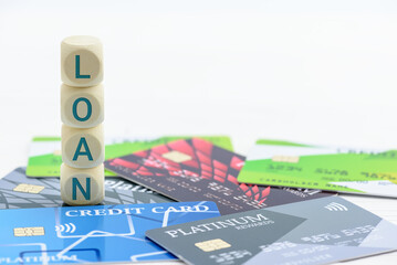 Credit card loan payment, personal finance, and consumer finance : Credit cards and a stack of wood blocks spelling "LOAN" depicting a focus on topics like credit score, money lending,  personal loan.