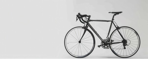 Fototapeta premium A sleek black bicycle is positioned against a minimalist background, showcasing its elegant design and features.