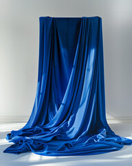 A blue curtain is draped over a wall. The curtain is long and flowing, creating a sense of movement and depth. The blue color of the curtain adds a calming and serene atmosphere to the scene