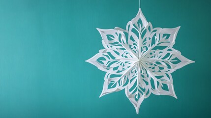 Obraz premium Intricately cut white paper flakes in mandala patterns, hanging in a symmetrical arrangement against a soft teal background