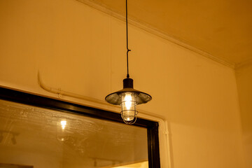 Close-up of a vintage-style pendant lamp with a warm glowing bulb and protective cage design. Perfect for industrial or retro-inspired interior decor.