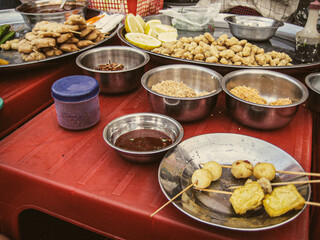 Selective focus, Yangon Myanmar (Burma). people sharing Traditional Burmese cuisine pork on a skewer ''wet tha dok hto'' dipped in brown souce. Street food sticky rice with fried onions and coconut