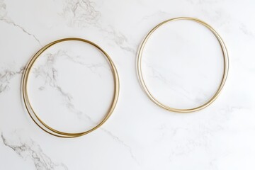 Two gold metal hoops on a marble surface, possibly for decorative or crafting purposes.