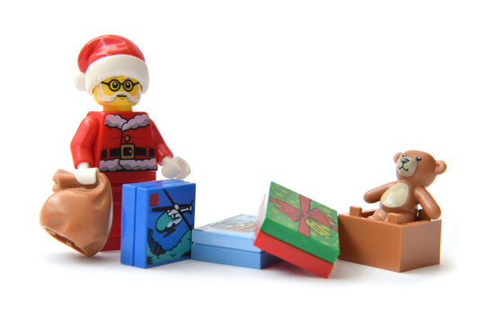 L&ouml;rrach, Germany - Dcember 4th 2024: Editorial illustrative image of lego minifigure of Santa Claus with bag and present boxes with teddy bear isolated on white.