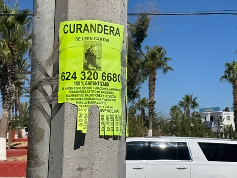 Los Cabos, Baja California Sur, Mexico. Dec 4, 2024. A bright yellow flyer advertising the services of a curandera, or spiritual healer, in Mexico. The flyer lists various services offered.
