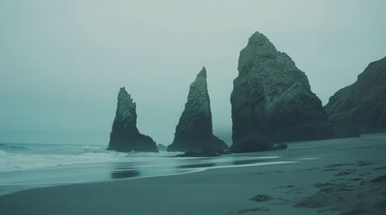 Misty beach scene with dramatic rock formations.