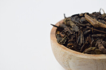 Close up view of dried tea leaves in wooden teak bowl isolated on white background. copy space, empty space, free space.