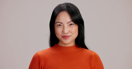 Wink, secret and face of woman in studio for gossip, privacy or mystery announcement with surprise. Happy, quiet and portrait of Japanese female person with silent hand gesture by gray background.