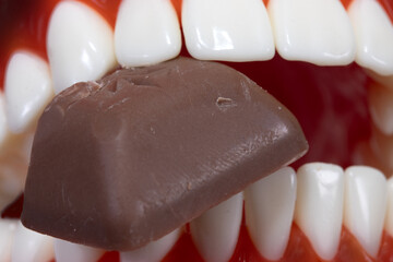 A chocolate candy between teeth, close up