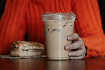 Woman Holding Iced Coffee and Bagel