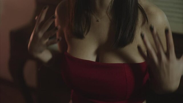Closeup of the breast  of  a young female artist wearing a sexy red top  passionately singing giving her back to an old-fashioned piano 
