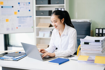 Asian Businesswoman Analyzing Finance on Tablet and Laptop at modern Office Desk tax