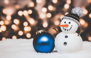 Cute snowman with blue Christmas ball in bokeh snow background