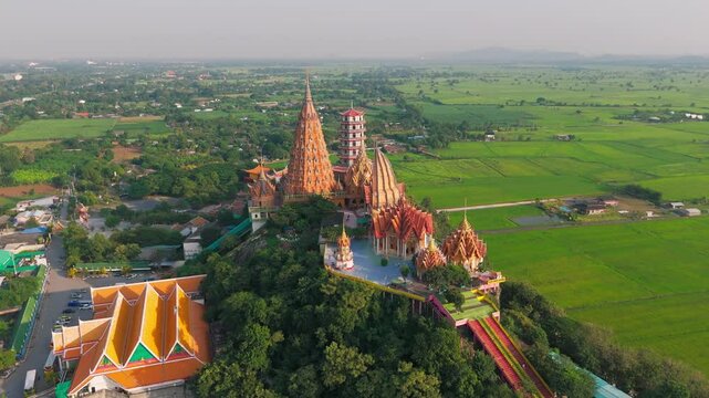drone rotate around Wat Tham Suea buddhist temple in Kanchanaburi Thailand at sunset