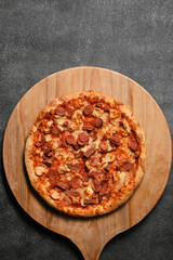 Grilled round flat pizza, covered in tomato and cheese sauce, mozzarella, meat, sausage and vegetables. This food originates from Italy - photographed from above (flat lay)