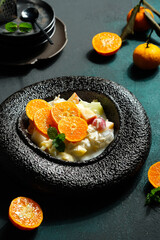 Salad often called fruit cocktail is a food made from chopped fruit and syrup, and served cold. This salad is topped with orange slices and mint leaves - Dark mood food photography