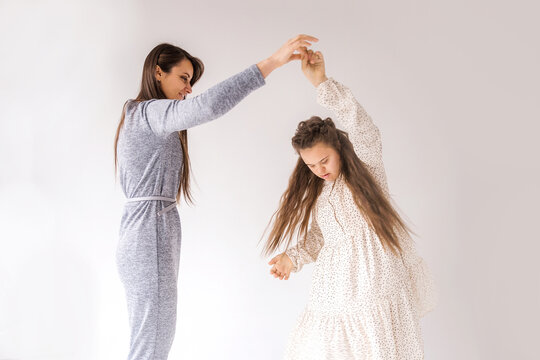 A heartwarming image of a mother and daughter sharing a joyful dance. The girl, who has Down syndrome, radiates happiness as she twirls with her loving mother against a clean white background
