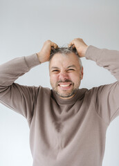 Obraz premium Close-up portrait of a man pulling at his hair in frustration or anger. His face is contorted in a grimace, showing his teeth, expressing intense negative emotion. 