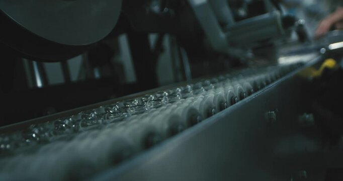 Close-up of vaccine vials moving along an automated production line in a sterile pharmaceutical manufacturing facility