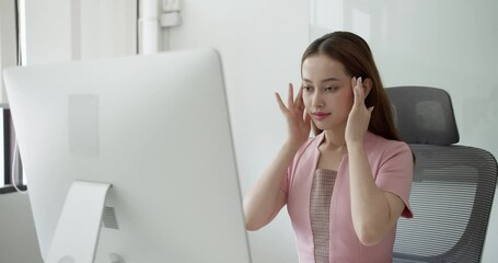 After extended hours of computer work, this office worker massages her head to reduce stress and regain focus.