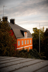 Old orange house with dark roof and trees around