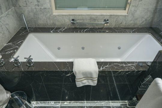 Super deluxe black and white marble bathroom of suite stateroom cabin onboard luxury ocean liner cruiseship cruise ship with sink, mirror, towels and whirlpool bath tub and rain shower 
