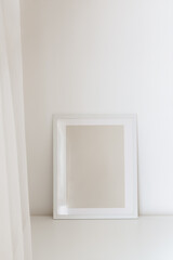 Modern frame on the white table against the wall. Frame mock up, copy space for your text or image 