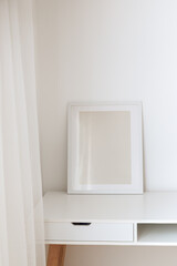 Modern frame on the white table against the wall. Frame mock up, copy space for your text.