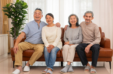 happy asian senior couple sitting on couch,talking together,elderly pensioner friends gathering in the living room at home