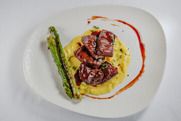 red wine sauce tenderloin served with smashed potatoes with onions and grilled asparagus, white plate and background