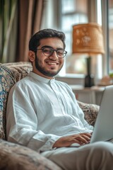 Man in traditional attire using laptop, indoors.