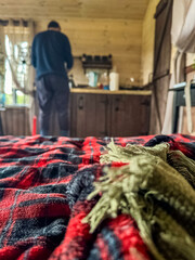 Cozy cabin life with plaid blanket and blurred kitchen with man background. High quality photo