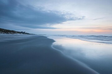 Fototapeta premium Serene beach landscape at twilight with gentle waves and soft clouds.