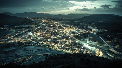 Obraz premium Nightfall Cityscape Aerial View of Illuminated City Nestled in Mountains.
