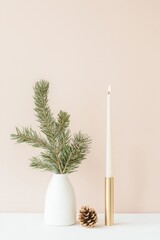 A white vase with pine needles and a candle in it