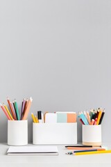 Fototapeta premium A white desk with a white box and three white pencil holders